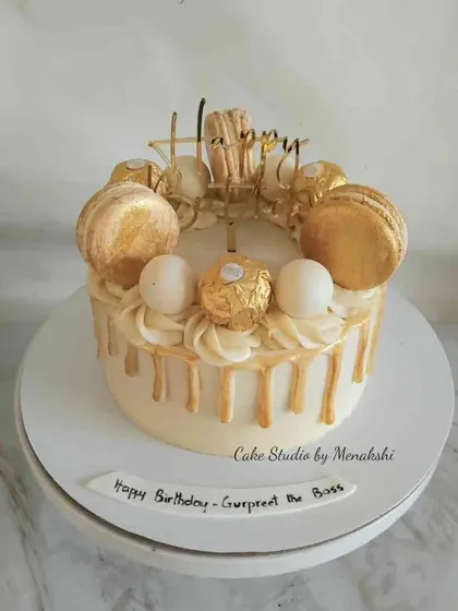 A classic white and gold drip cake made completely without fondant. This design is topped with golden macarons and Ferrero Rocher chocolates for an extra touch of luxury.