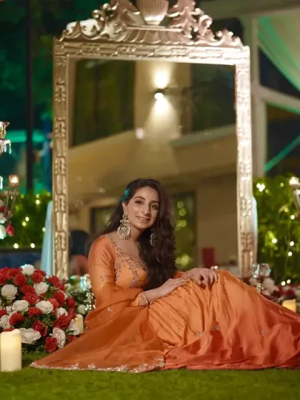 The bride looking radiant and beautiful, seated in a regal setting of flowers and candles.