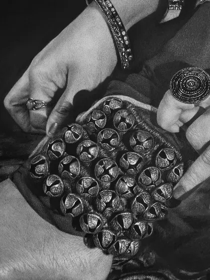 This close-up focuses on the hands and the dense cluster of bells on the ghungroo, showcasing the hyperrealistic detail achieved with pencil work.