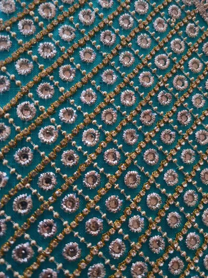 A close-up of the finished embroidery, showcasing the geometric pattern created with mirror work and thread, turning a simple fabric into a timeless expression of elegance.