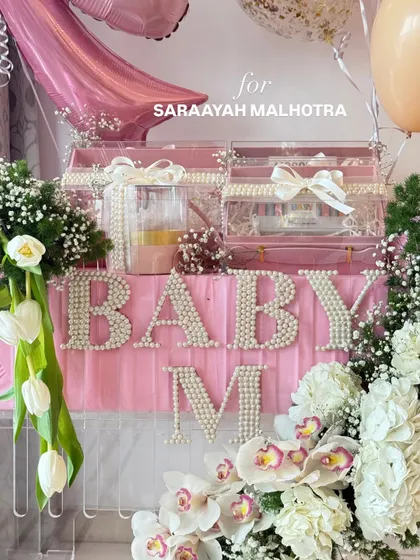 A detailed shot of the 'Baby M' hamper, focusing on the pearl lettering and the fresh white tulips and orchids.
