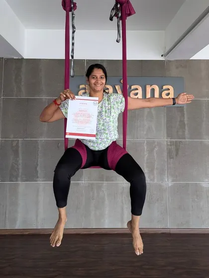 Another happy graduate, sitting proudly in the hammock with her well-earned aerial yoga teaching certificate.
