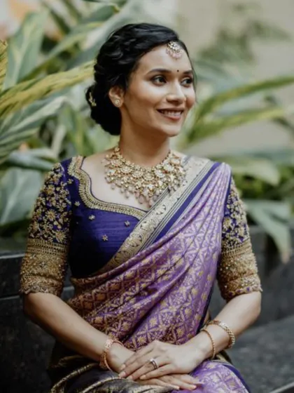 A lovely candid of the bride, seated outdoors. Her braided updo and soft makeup look effortlessly beautiful in the natural setting.