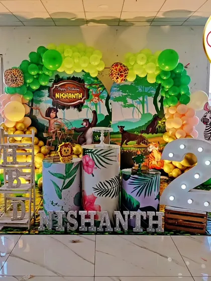 A full view of a Jungle Book-themed second birthday. The setup includes a character backdrop, themed plinths, and a large light-up number '2'.