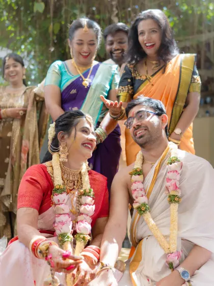 A moment of pure joy and laughter, with family members blessing and teasing the couple during a wedding ritual.