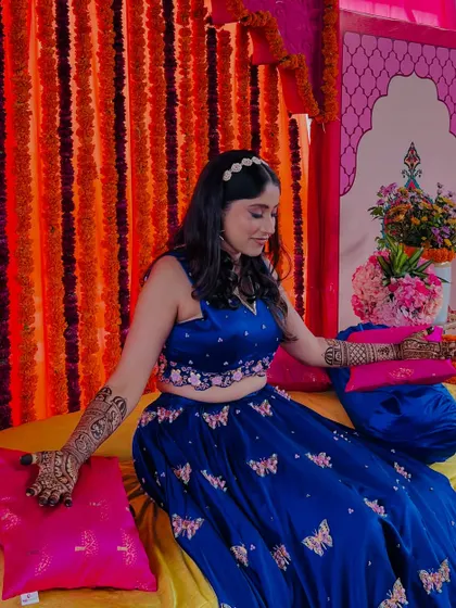 A candid moment of Supritha admiring her bridal mehendi, surrounded by colorful decor.