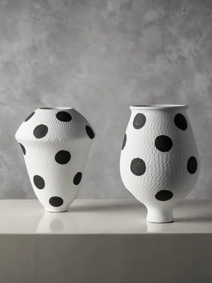 Here are two variations of our polka dot ceramic vases. Their contrasting shapes, one wide and one tall, create a dynamic pairing that adds a touch of whimsy and graphic appeal to a console or shelf.