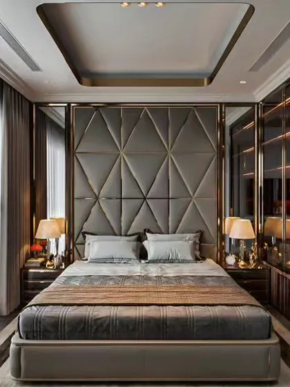 A sophisticated bedroom with a geometric padded headboard and a tray ceiling design. The room features integrated wardrobes with glass doors and elegant bedside lamps.