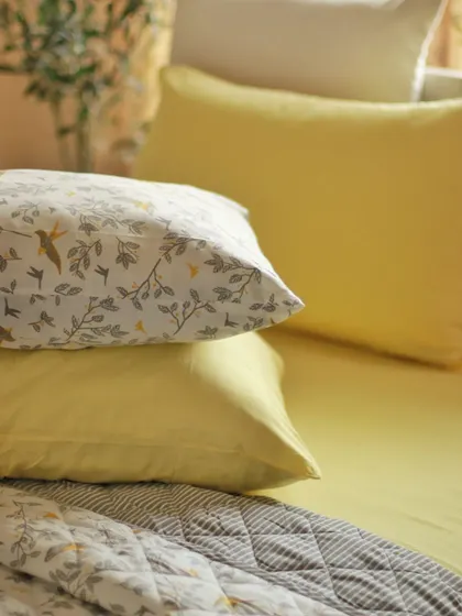 The soft texture of our 100% cotton pillowcases is perfect for a restful night's sleep. Here, our 'Winged Skies' pillowcase is stacked with a solid yellow one, showing how easy it is to mix and match our collections.