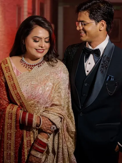 The happy couple at their reception. Her glamorous makeup stands out beautifully next to his classic tuxedo, creating a picture-perfect moment.