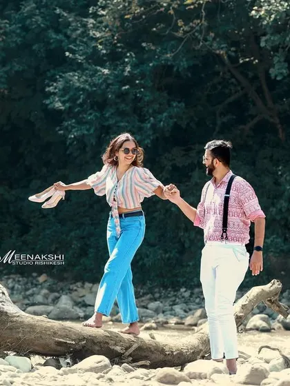 A playful moment captured as a couple walks along a fallen tree trunk near a stream. This shows how we can use natural elements to create fun and interactive shots.