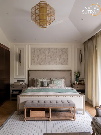 A full view of the symmetrically designed master bedroom. The space is a perfect balance of subtle luxury, with wall paneling, and rustic soul, with warm wooden furniture and natural textures.