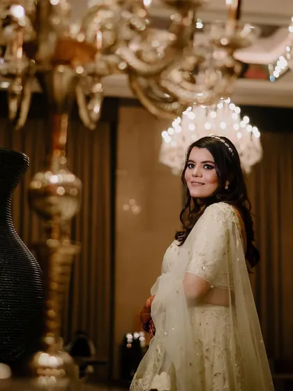 An elegant portrait of the bride under the warm light of a grand chandelier.