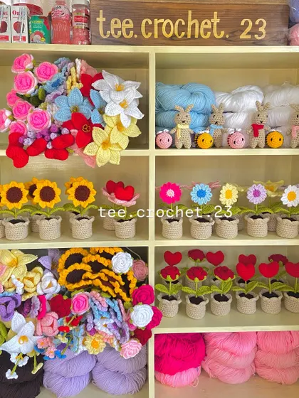 A wide view of my workshop shelves, showcasing a mix of potted flowers, amigurumi, and yarn.