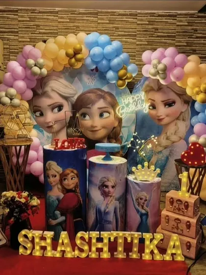Let it go with our Frozen themed party decor. This setup for Shashtika's first birthday features Elsa, Anna, and Olaf with a blue and purple balloon arch that looks like a winter wonderland.