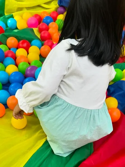 A child sits amidst a sea of colorful balls on our play parachute. This was a fun, water-free way to celebrate the joy and vibrancy of Holi.