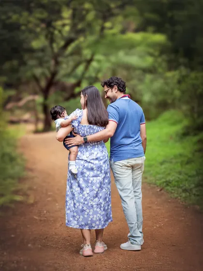 A family of three is seen from behind, walking down a path in the woods. This image evokes a sense of journey and togetherness, a quiet moment of a family moving forward in life.