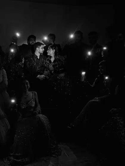 A creative group shot from a Sangeet night, with friends lighting up the couple with their phones. It's a modern and intimate take on a group portrait.