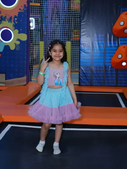 Dressed for fun, a young girl poses in our interactive trampoline zone, ready for an afternoon of play.