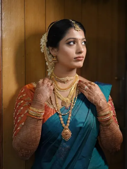Adjusting the final piece of jewelry. This look features layered necklaces, and the makeup is balanced to complement the ornate accessories without being overpowering.