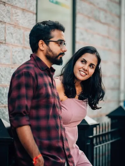 A playful, peeking glance from the bride-to-be during a casual pre-wedding shoot on a city street.