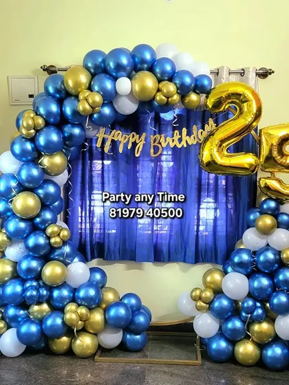 A 25th birthday decoration with a blue, white, and gold balloon arch.