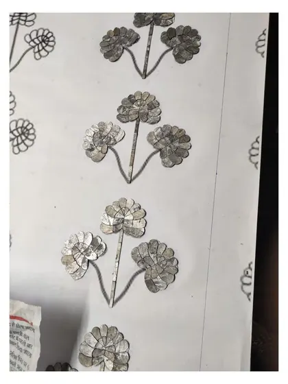 A detailed shot of the Thikri glass pieces being applied to the backing, following the hand-drawn floral pattern.