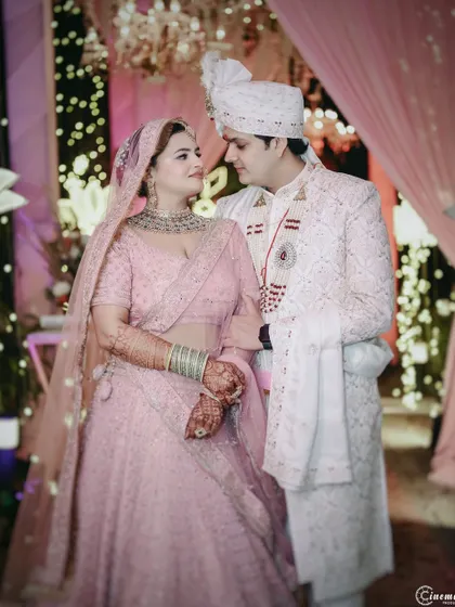 An elegant portrait of the couple against a backdrop of soft pink drapes and fairy lights, creating a romantic and dreamy atmosphere.