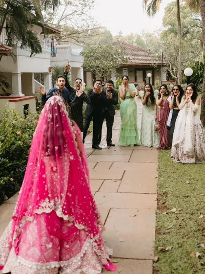 A beautiful "first look" moment where the bride, in a stunning pink lehenga, is revealed to her emotional friends and family.
