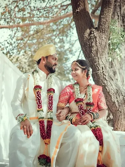 A serene portrait of a couple sitting under a tree after their wedding ceremony, sharing a quiet look of love.