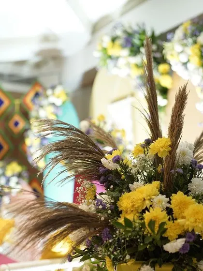 A close-up of the floral arrangements for a Mehendi, featuring a mix of yellow chrysanthemums, pampas grass, and other wildflowers for a bohemian-chic look.