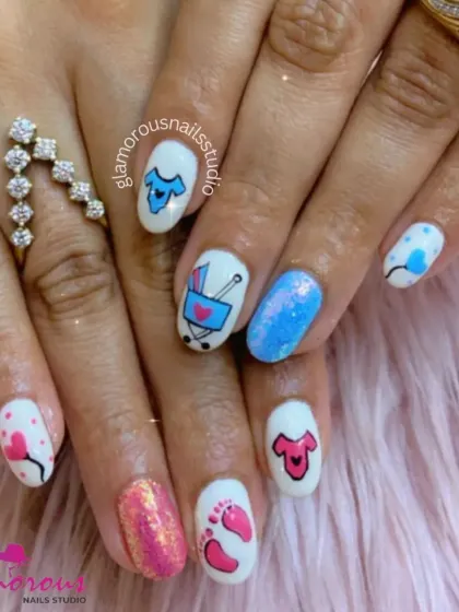 A full set of adorable baby shower nails! We used a white base to make the pink and blue hand-painted art pop, featuring tiny clothes, a stroller, and little footprints. The glittery pink and blue accent nails add the perfect amount of sparkle.
