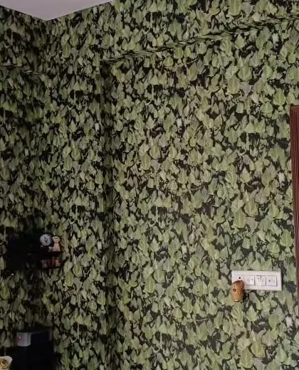 A room with a dark wallpaper covered in a dense green ivy-like pattern, creating a rich and textured look.