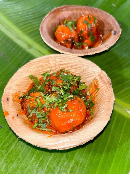 A single serving of my Hot Sizzling Bonda, garnished with fresh cilantro and served in an eco-friendly leaf bowl. It's a modern take on a traditional South Indian snack.