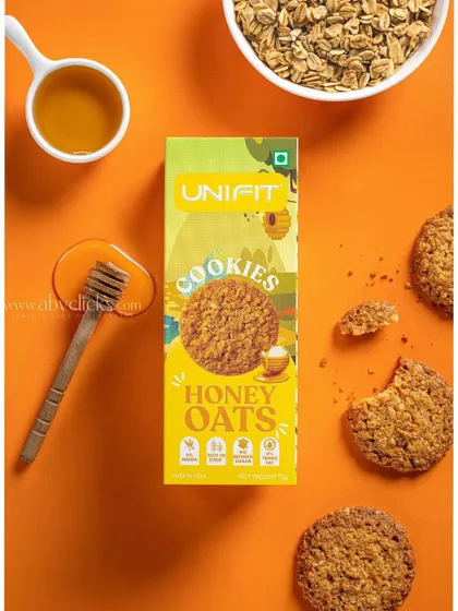A Unifit honey oats cookie box, styled with a honey dipper and oats for a natural, healthy feel.