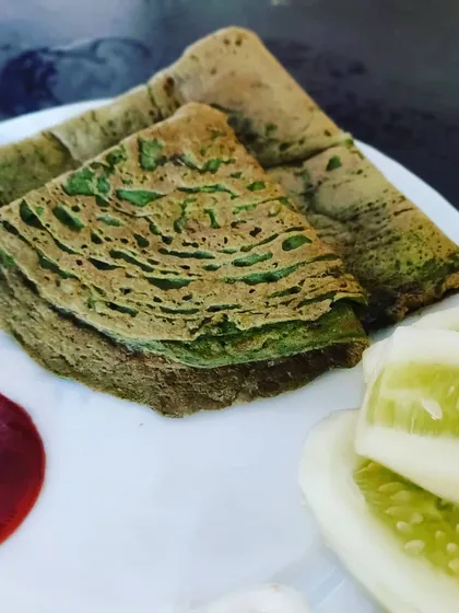 Healthy and protein-packed Besan Palak Chilla (spinach and gram flour crepes) served with ketchup and fresh cucumber slices.