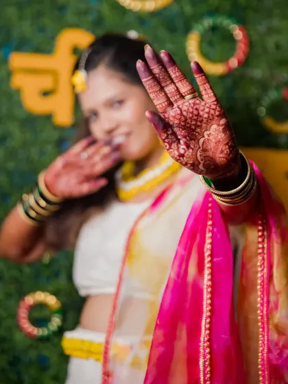 A creative shot focusing on the bride's mehendi-adorned hand during her Haldi ceremony.