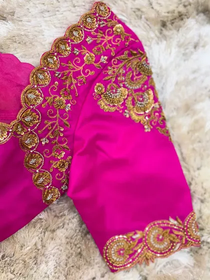 A close-up of the sleeve cuff of the pink blouse, detailed with circular motifs and scalloped edging.