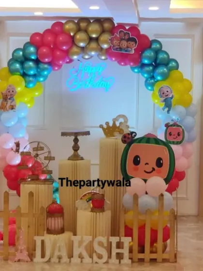 A colorful Cocomelon party with a rainbow balloon arch and a large character balloon.