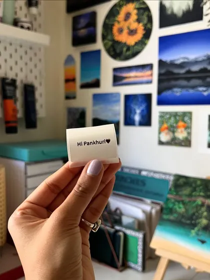 Holding up a small, personalized sticker. These little things bring me so much joy.