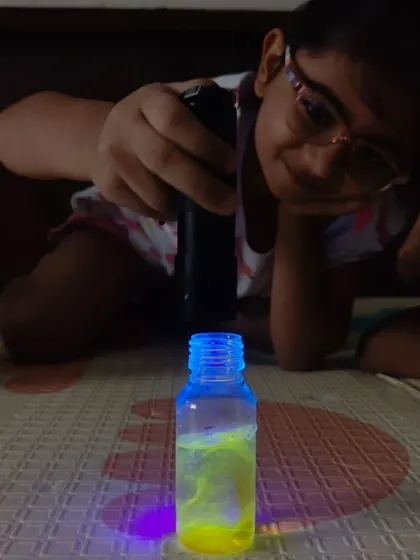 A young scientist completely absorbed in her experiment. Using a UV light, she discovers the magical glowing properties of her creation, a perfect example of screen-free, hands-on learning.