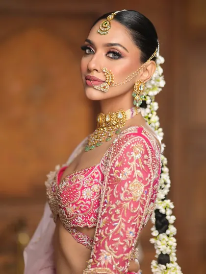 A side view highlighting the intricate floral braid and the sharp, elegant eye makeup. The look is both traditional and incredibly glamorous.