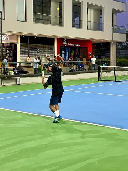 A player unleashes a powerful overhead smash during a weekend tournament, with spectators watching in the background.