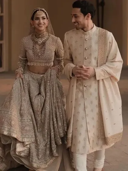 This couple wanted a soft, elegant look. I designed a beautiful beige lehenga with full-sleeve embroidery and a matching sherwani with subtle, complementary details.