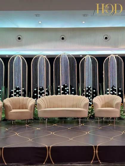 A closer view of the modern stage, focusing on the elegant shell-backed sofa and armchairs that add a touch of art deco glamour.