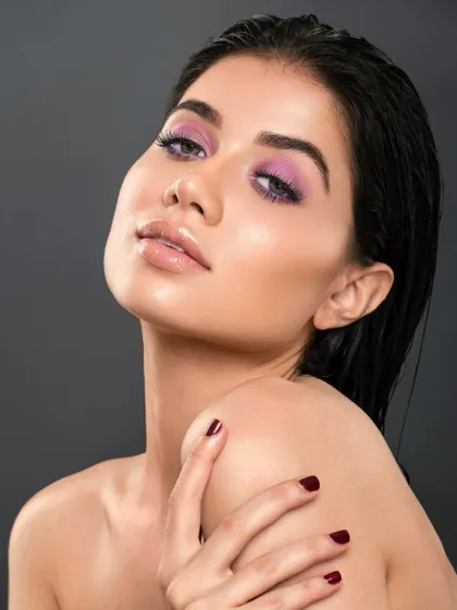 A classic beauty pose that highlights the model's shoulder and the elegant line of her neck. The focus remains on the sophisticated purple makeup and the overall polished feel of the portrait.