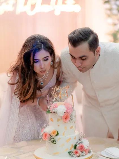 The couple makes a wish together as they blow out the candles on their beautiful engagement cake.