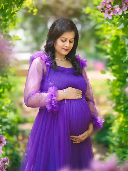 A dreamy outdoor portrait in a purple gown, with the mom-to-be framed by a natural arch of flowers and greenery.