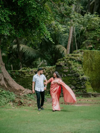 A dynamic shot of a couple walking in a park, with the bride's saree flowing behind her.