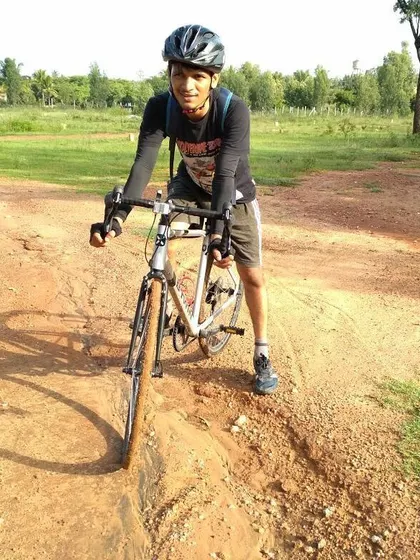 A rider carefully maneuvering his road bike through a rutted dirt path, showing the challenging yet fun nature of our mixed-terrain rides.